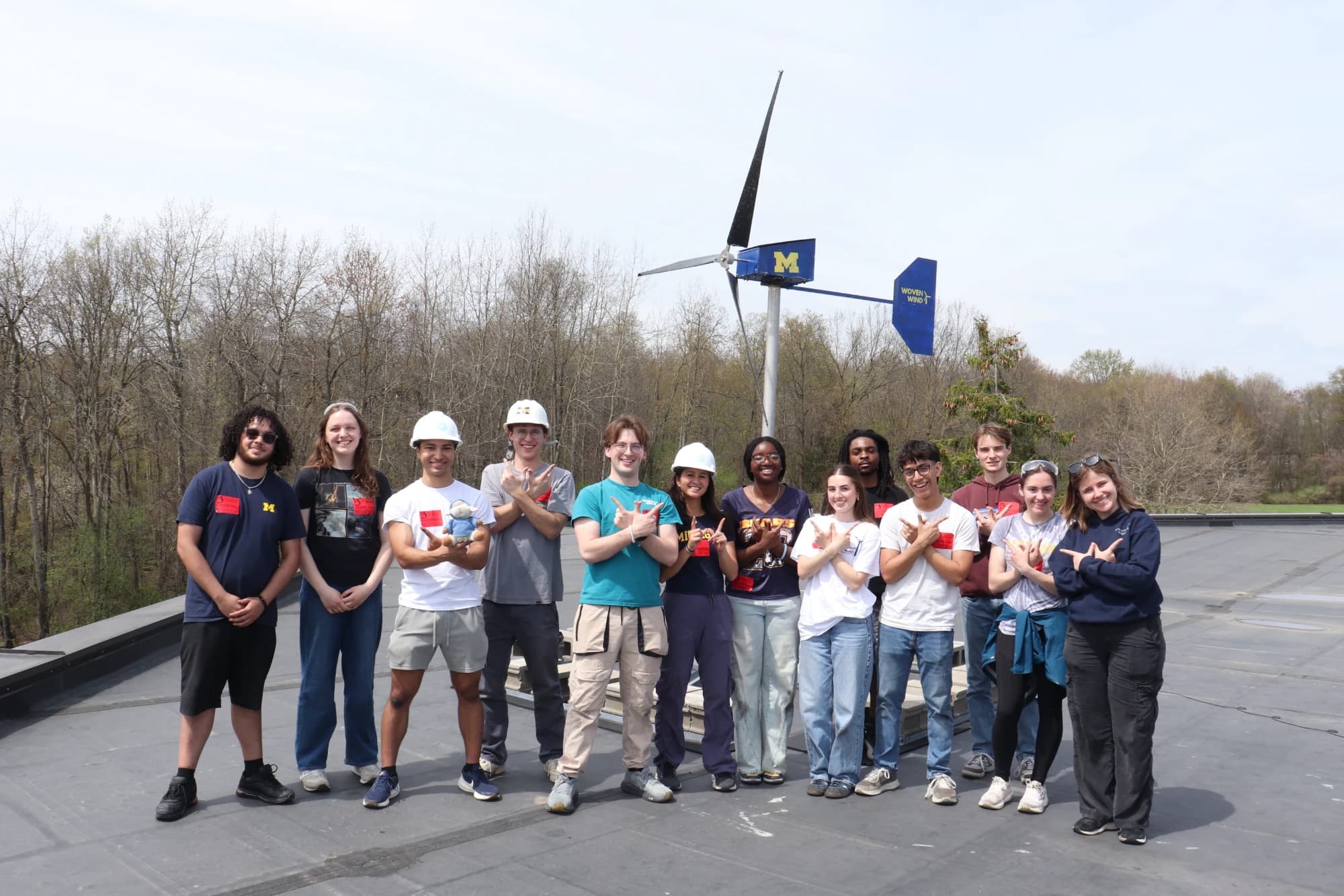 Team photo on a rooftop in front of the wind turbine